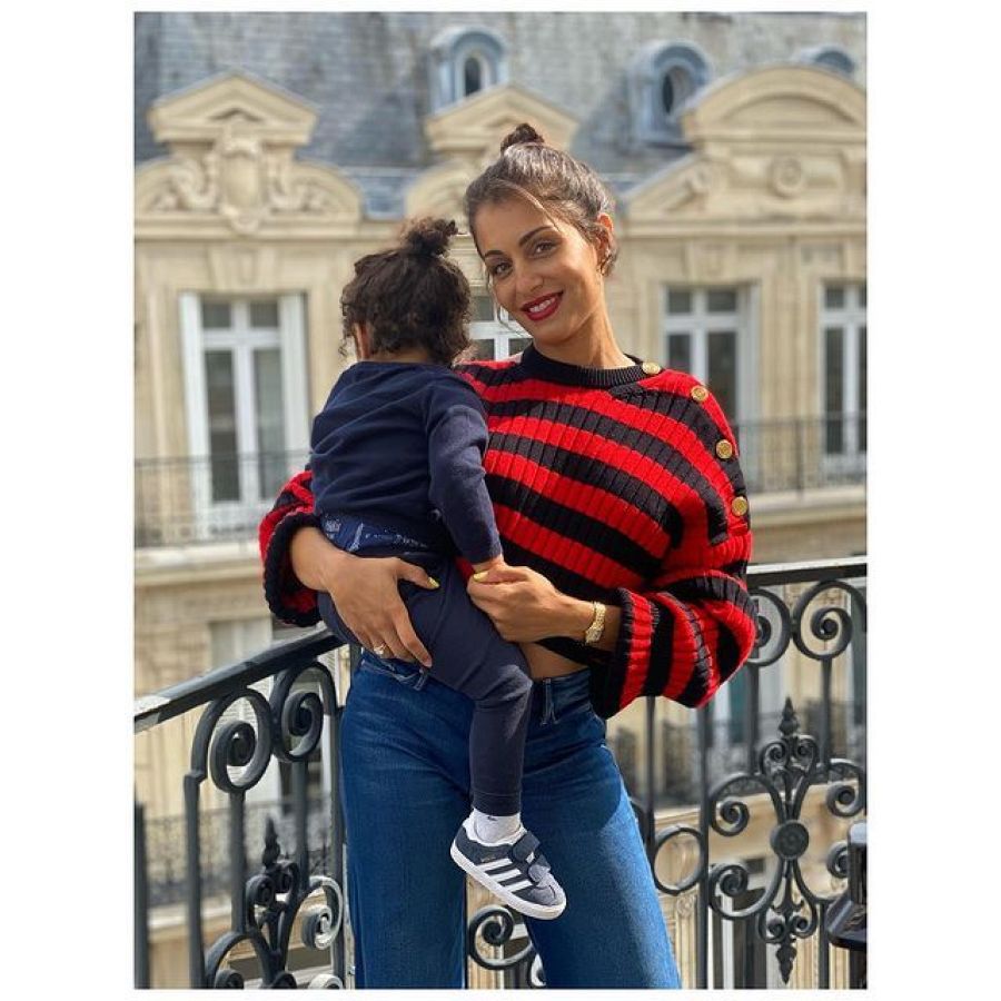 Hiba Abouk con su hijo en brazos y una camiseta roja y negra a rayas
