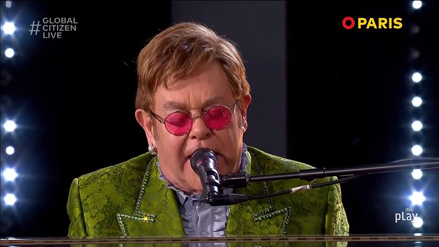 Elton John con gafas de sol y un traje verde tocando el piano sobre el escenario del Global Citizen Live 2021
