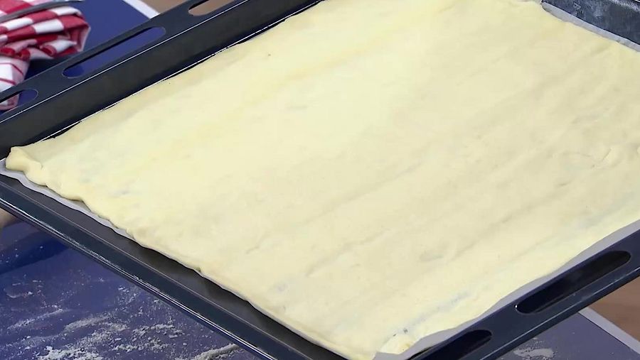 Masa de pizza estirada en una bandeja de horno.