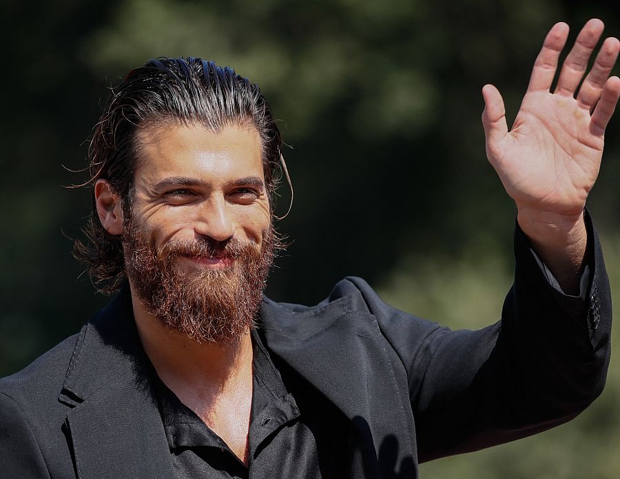 Can Yaman, sonriente, saluda con una mano