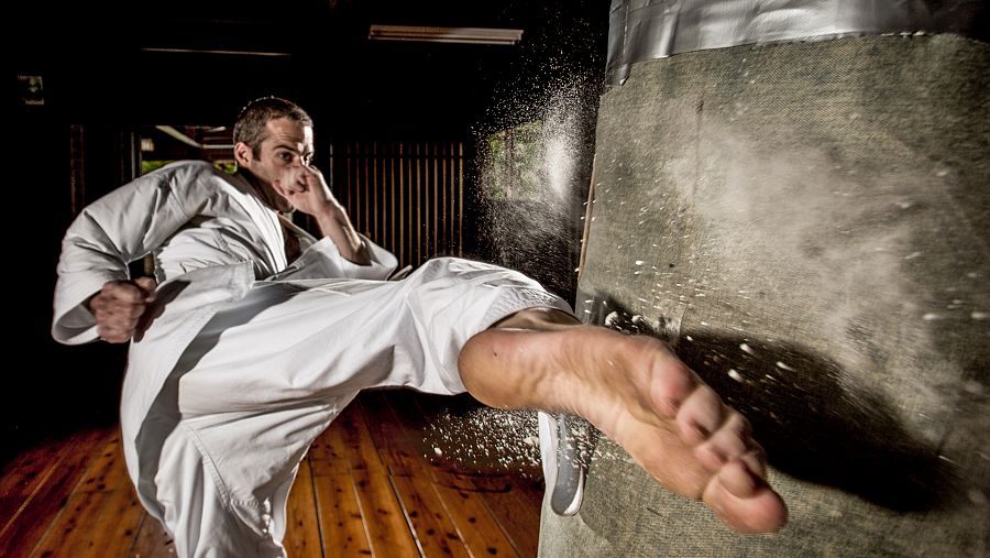 Un karateka golpea con el pie una barra de cemento