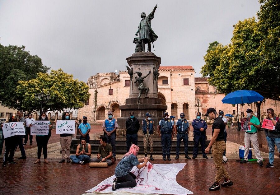 Personas protestan junto a una estatua de Cristóbal Colón en Santo Domingo