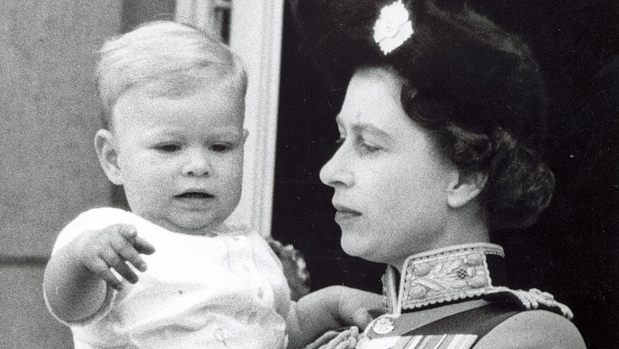 La reina de Inglaterra, Isabel II, sostiene en sus brazo al príncipe Andrés.