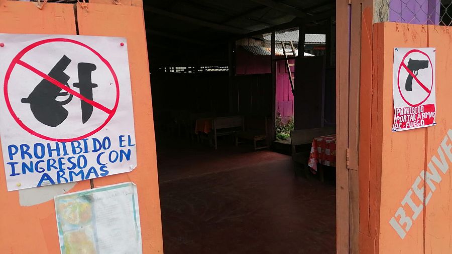 Sendos carteles caseros, en ambos lados de la puerta, prohiben el acceso con armas de fuego.