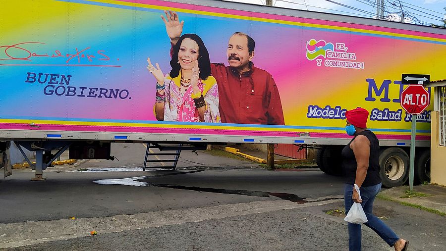 Una mujer camina frente a un camión con la imagen electoral del presidente nicaragüense, Daniel Ortega, y de su mujer y vicepresidenta, Rosario Murillo.