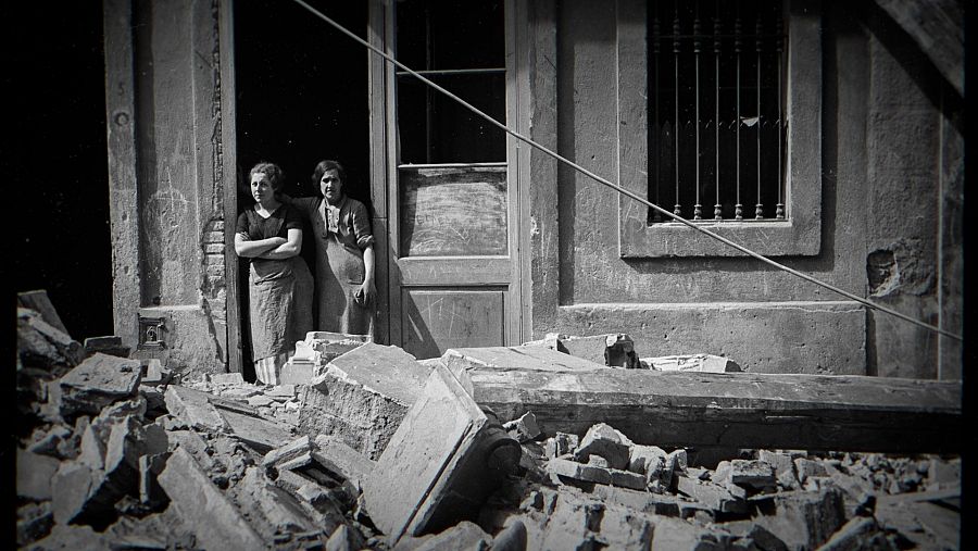 Dos mujeres en la puerta de un edificio con escombros delante, foto de Antoni Campañà