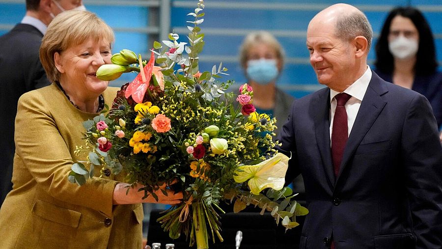 La todavía canciller de Alemania Angela Merkel recibe un ramo de flores del ministro de finanzas y líder del SPD Olaf Scholz en el que puede ser su último Consejo de Ministros. Foto: Markus Schreiber / POOL / AFP