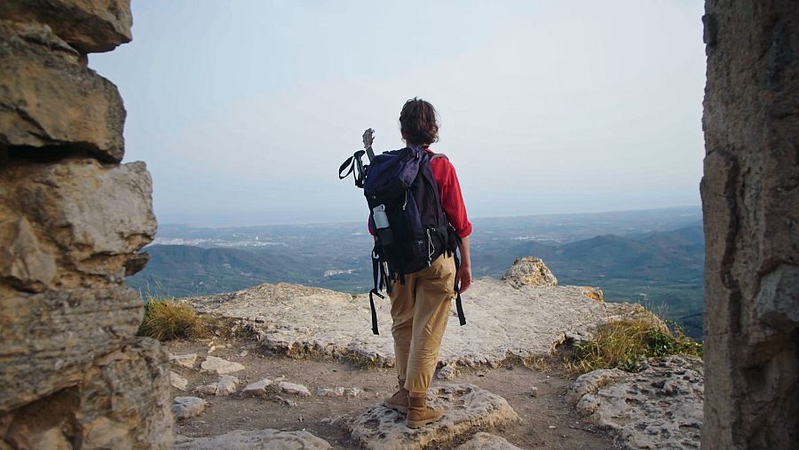 Anna Bertran d'esquenes en un cim mirant el paisatge