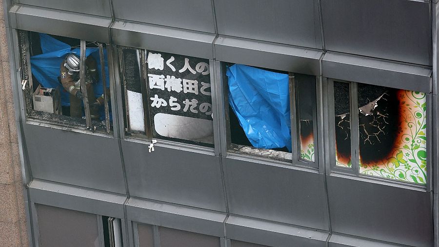 Detalle exterior de la planta que ha sufrido el incendio con un bombero en la ventana.