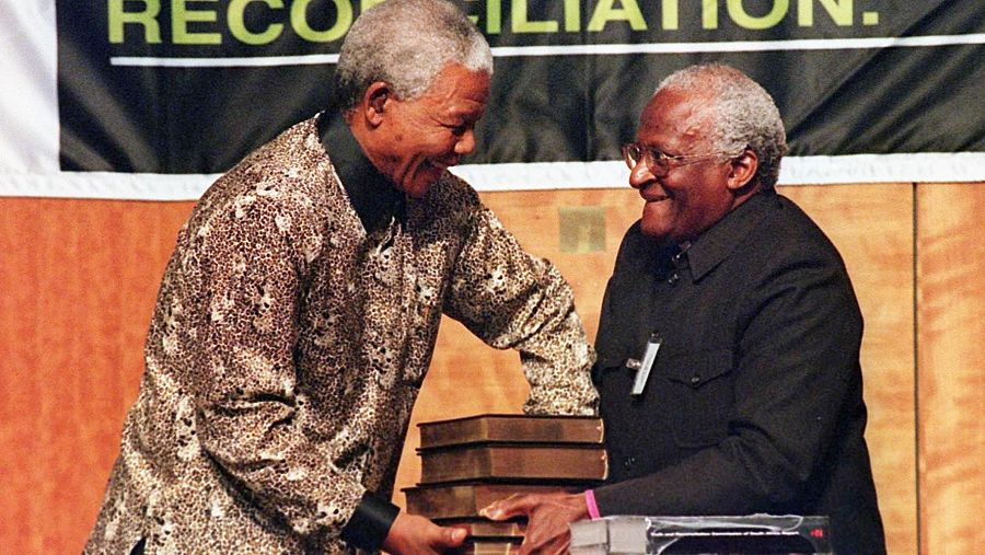 Desmond Tutu entrega a Nelson Mandela los cinco volúmenes del informe final de la Comisión de la Verdad y la Reconciliación en octubre de 1998.