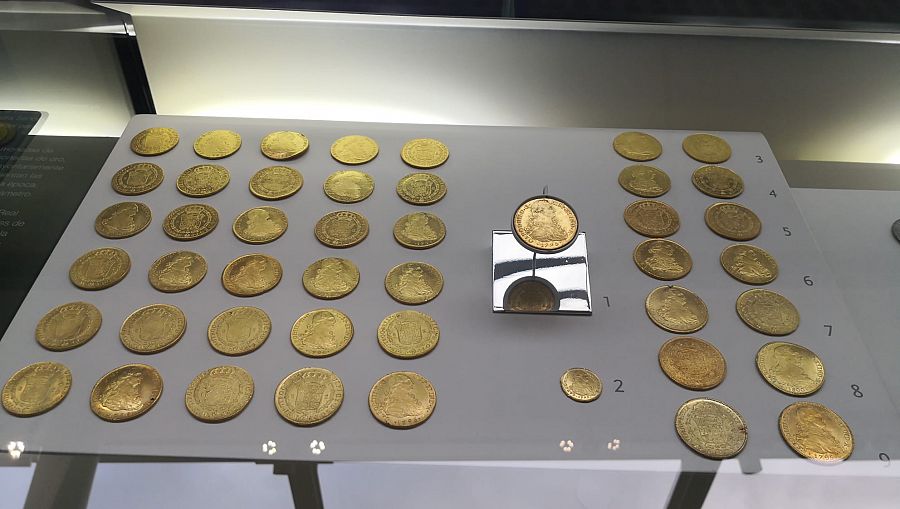 Monedas restauradas procedentes del Tesoro de las Mercedes en unas vitrinas de un museo.