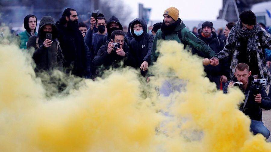 Manifestantes observan el humo de una bengala durante una protesta contra las restricciones en Bruselas.
