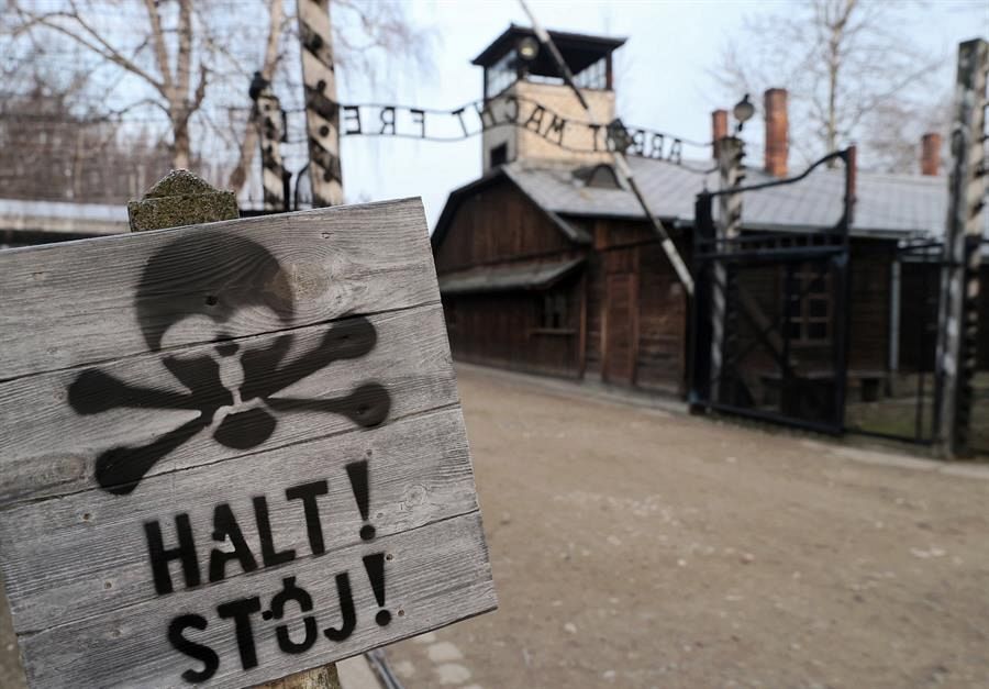 Campo de Auschwitz-Birkenau con una señal de peligro en primer término.