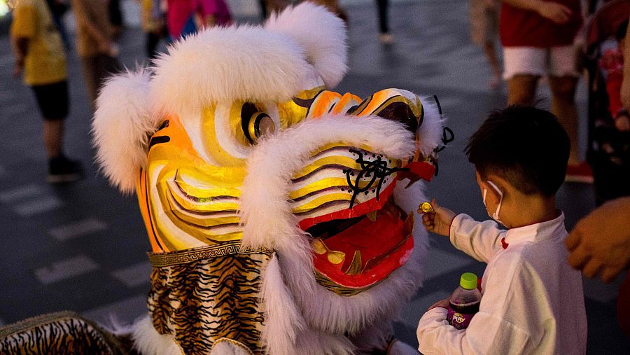 Un niño hace una ofrenda a un bailarín disfrazado en Bangkok, Tailandia