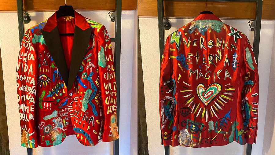 Chaqueta del esmoquin rojo que Aldo Comas ha llevado a los Goya 2022. Un homenaje a Verónica Forqué. El traje ha sido diseñado por Juan Avellaneda y pintado por el propio Comas. Se puede leer en la parte trasera: 