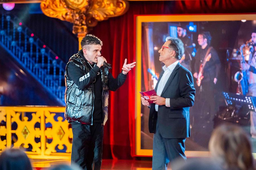 Arkano cantant amb el micro a la ma i davant escoltant Jordi Hurtado, a l'escenari