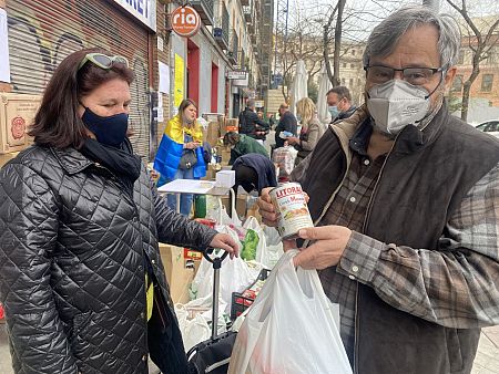 Teresa y Jesús muestran una de las latas de cocido madrileño que han entregado dentro de sus bolsas.