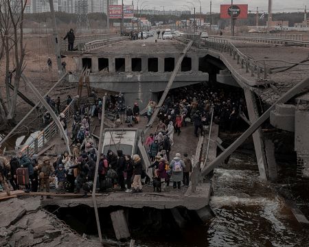 Civiles cruzan un puente destrozado cuando intentan abandonar Irpin, este sábado.