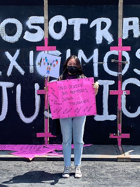 Ana posa mientras sujeta una pancarta morada en México