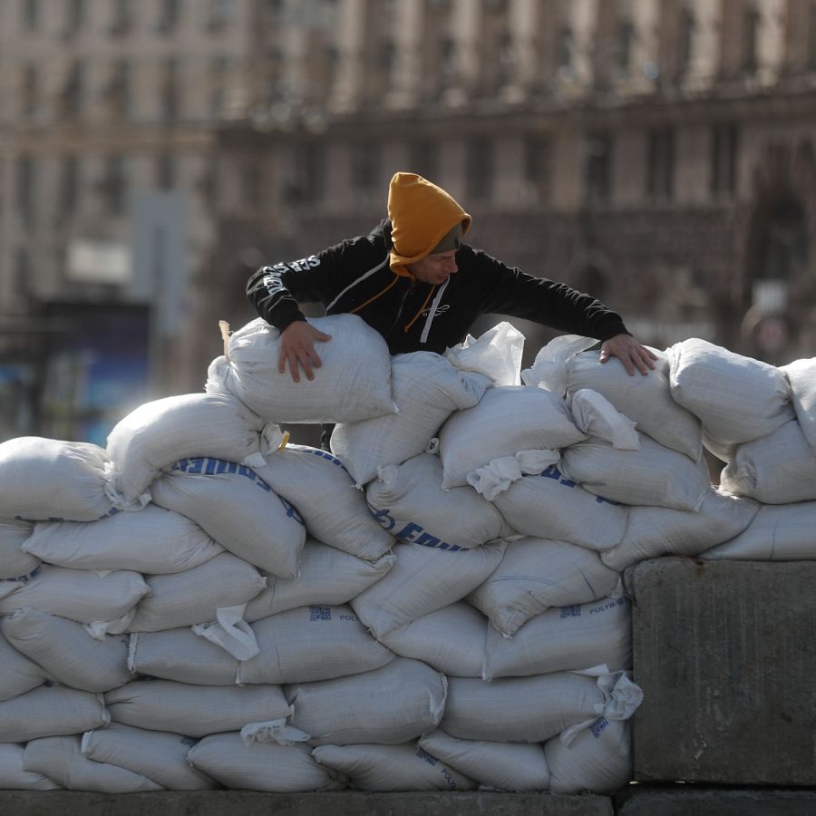 Un hombre construye una barrera de sacos de arena en una calle céntrica en Kiev.