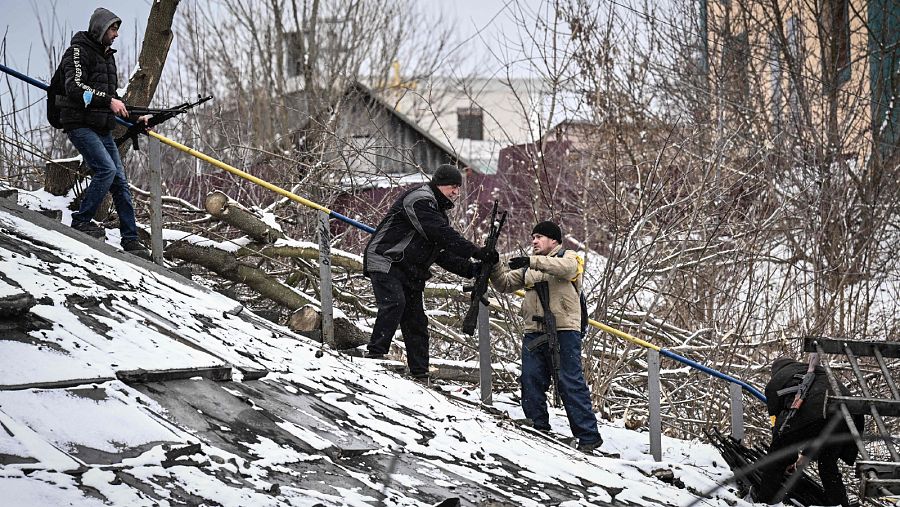 Milicianos ucranianos pasan rifles de asalto por un puente derruido (1 marzo).