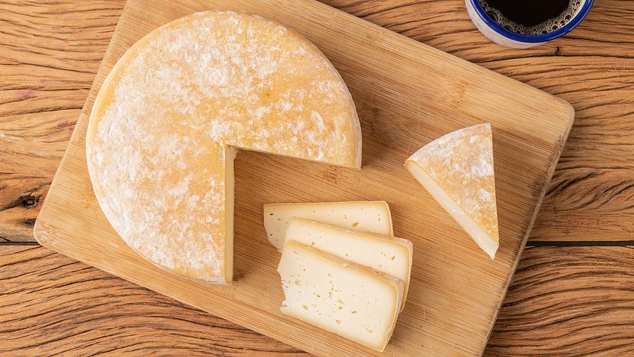 Una pieza de queso cortada en cuñas sobre un cortador de madera
