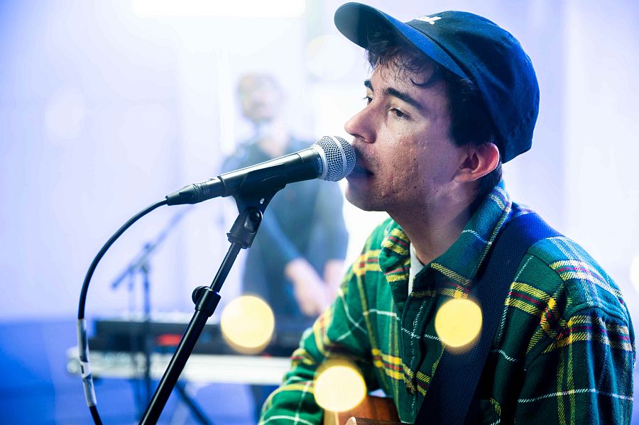 Ferran Palau cantant dvant del micròfon, darrere, en segon pla, el músic del teclat