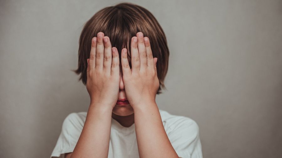 Niño tapándose la cara