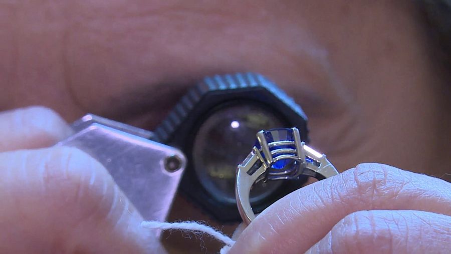 Primer plano del ojo de un tasador examinando un anillo con una lente especial.