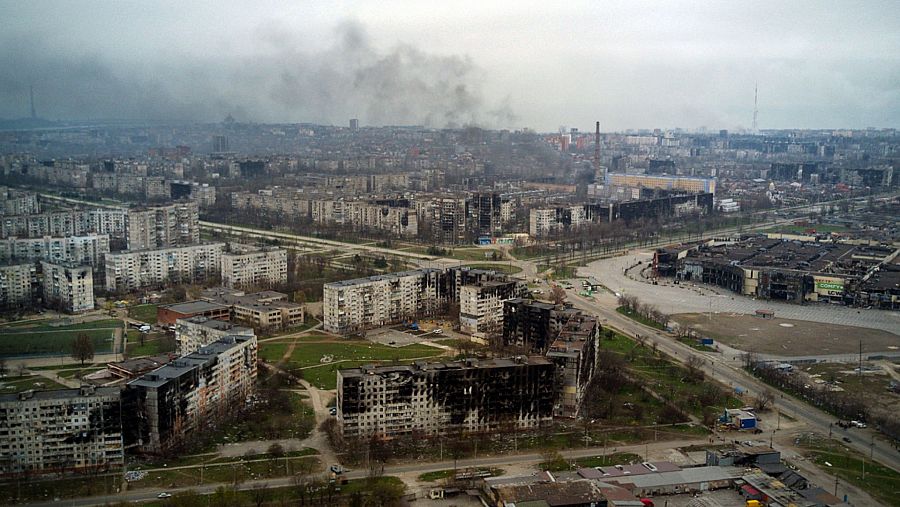 Una foto aérea de Mariúpol donde se ven edificios destrozados y una columna de humo negro.
