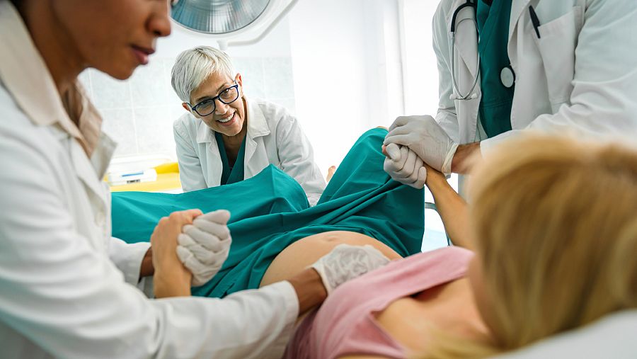 Varios sanitarios asistiendo a una mujer dando a luz