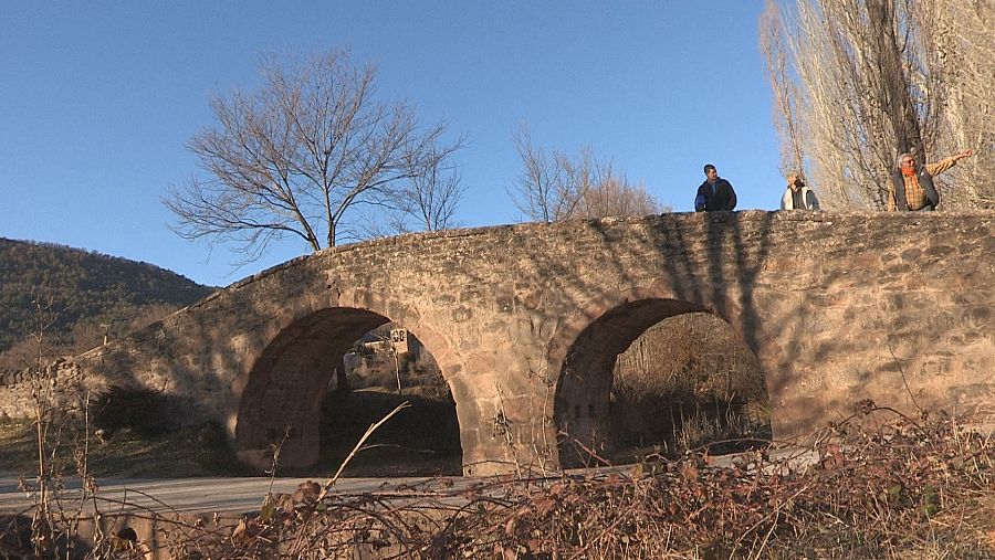 Tres personas sobre un puente de piedra en Bara, localidad del Pirineo de Huesca.