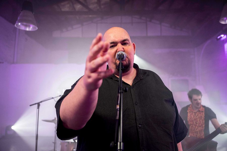 Primer pla del cantat amb el micròfon i darrere el baixista