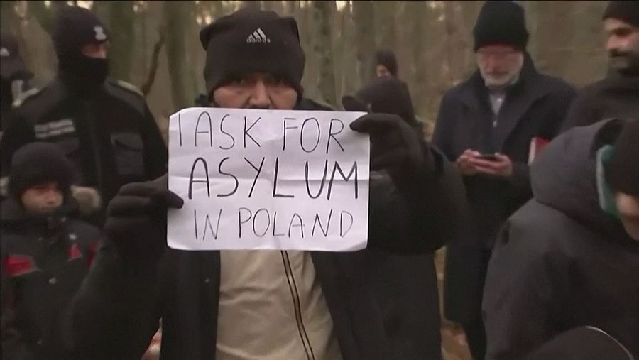 Un inmigrante bielorruso muestra un cartel pidiendo asilo en Polonia.