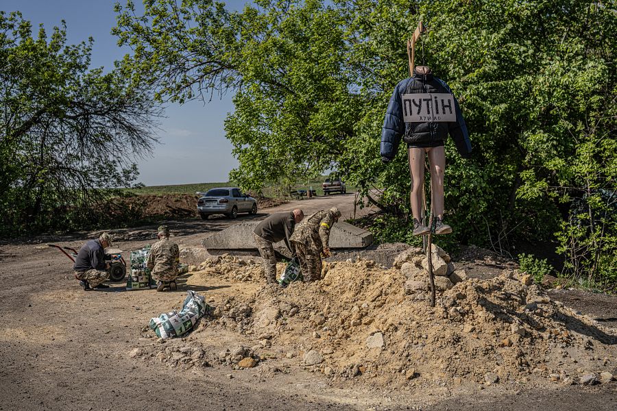 Un grupo de soldados construyen una barricada junto a un puesto de control en Ucrania donde se encuentra colgado un maniquí que representa a Vladimir Putin 