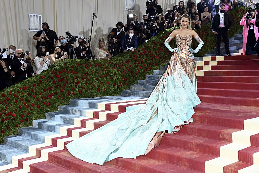 Blake Lively lució un vestido transformable de Versace en la Met Gala 2022. Su look pasaba de un vestido ceñido de color bronce, a un vestido con una larga cola y detalles en turquesa.