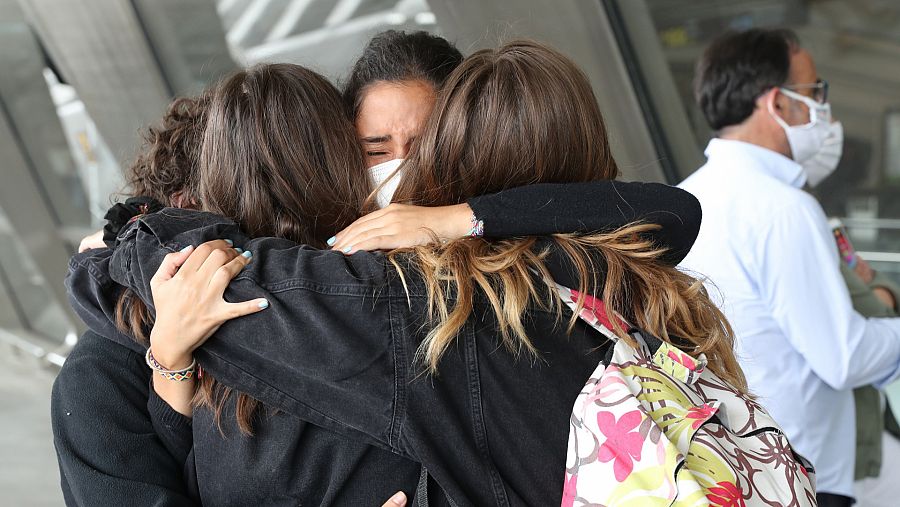 Un grupo de amigas se abraza en un aeropuerto