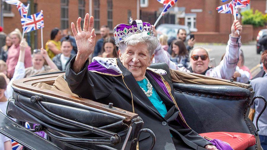 Una mujer sentada en una carroza con una corona saluda al público durante las celebraciones del Jubileo de Platino en Belfast