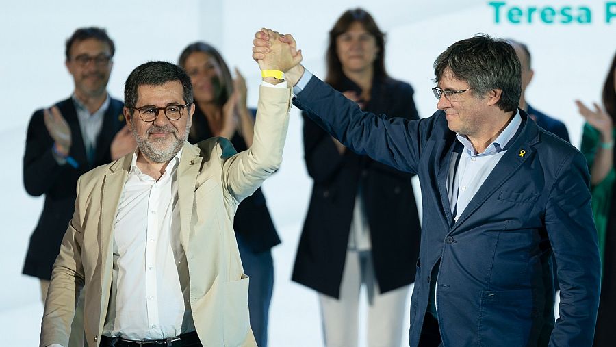 El hasta ahora secretario general de JxCat Jordi Sànchez toma de la mano al expresidente de la formación, Carles Puigdemont, durante el congreso celebrado en Argelers, en el sur de Francia.