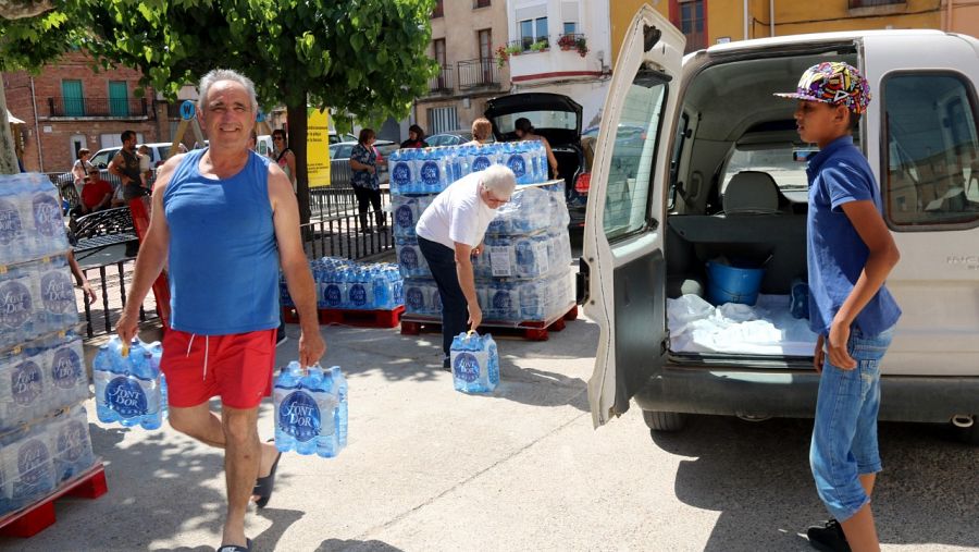 Un veí de Bovera transporta dos paquets d'aigua embotellada oferta per l'Ajuntament