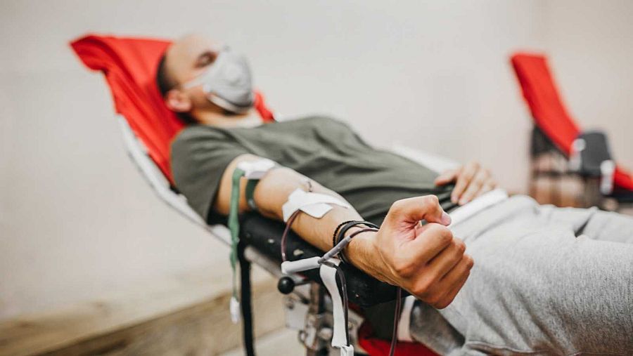 Un hombre tumado en una camilla mientras dona sangre