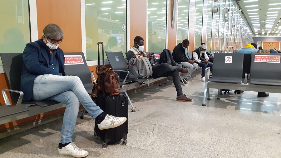 Hombre sentado en la sala de espera de un aeropuerto mirando el teléfono móvil