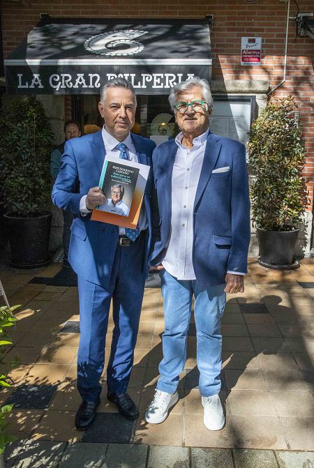 Pepe Domingo Castaño y Jenaro Castro posan con la biografía del locutor a las puertas de La gran pulpería.