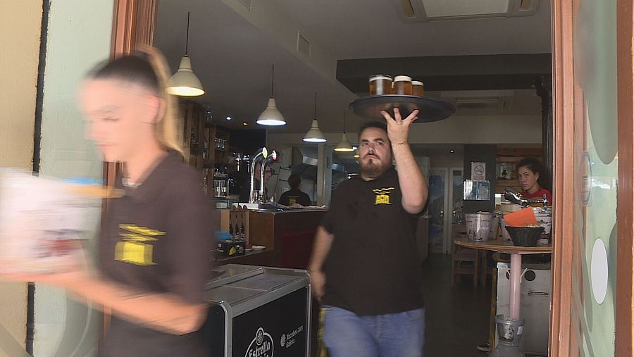 Dos camareros salen de un bar con la bandeja en la mano para servir a los clientes