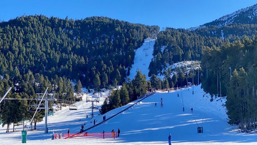 Diversos esquiadors baixant per una de les pistes de Masella (Cerdanya) i altres persones pujades a un teleesquí de l'estació.