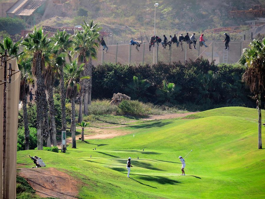 Intento de salto de la valla de Melilla en 2014, donde hay campo de golf y una decena de migrantes subidos a la valla para evitar ser arrestados