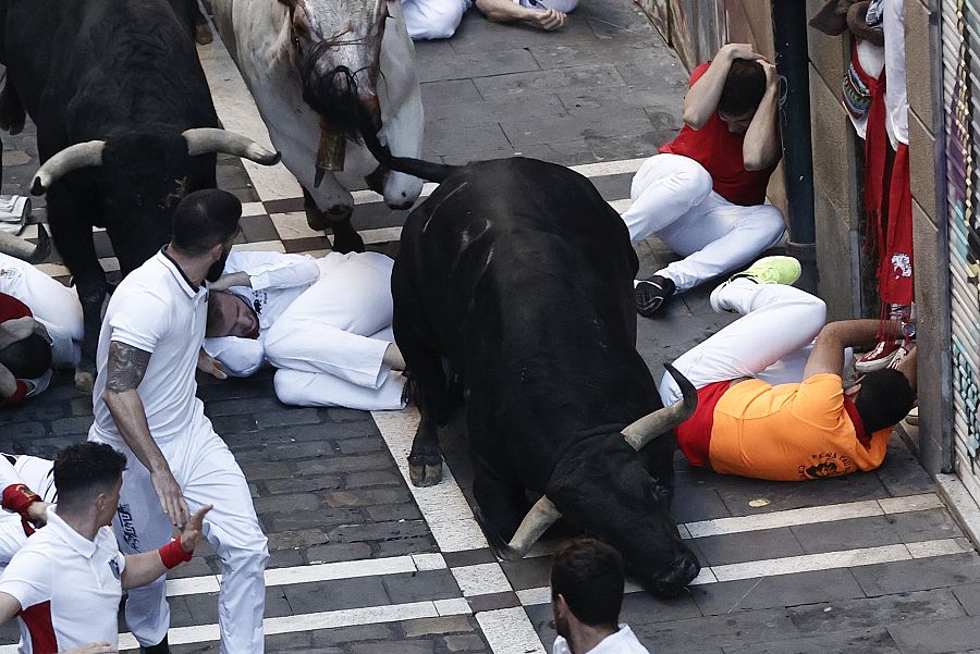 Un toro de la ganadería gaditana de Fuente Ymbro tropieza con varios corredores su paso por la calle de la Estafeta.