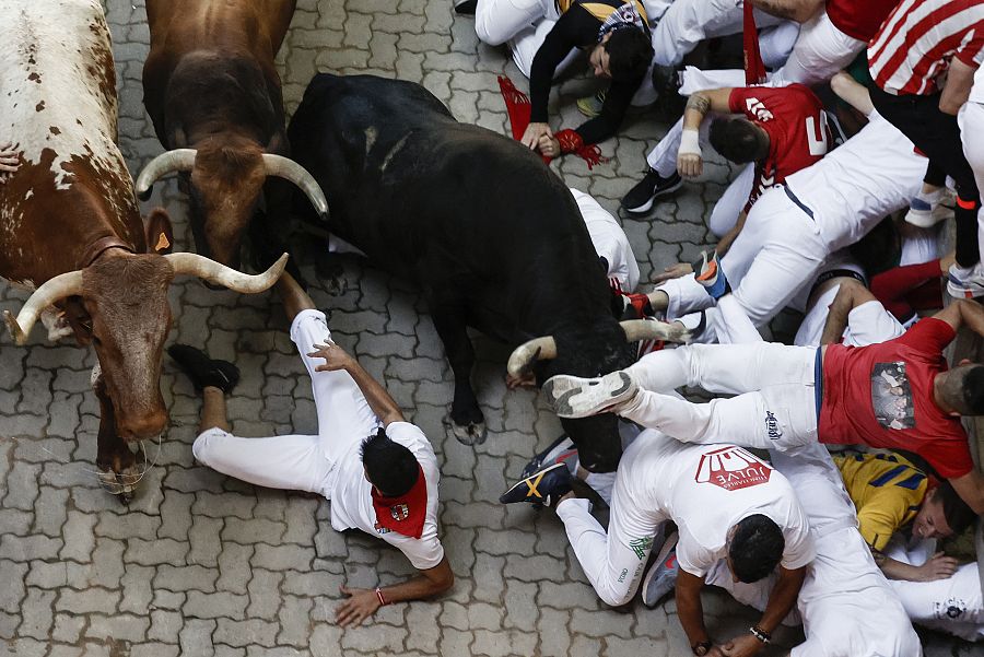 Mozos caídos en la entrada al callejón, donde varios toros se han volteado y los mozos han chocado con ellos. 