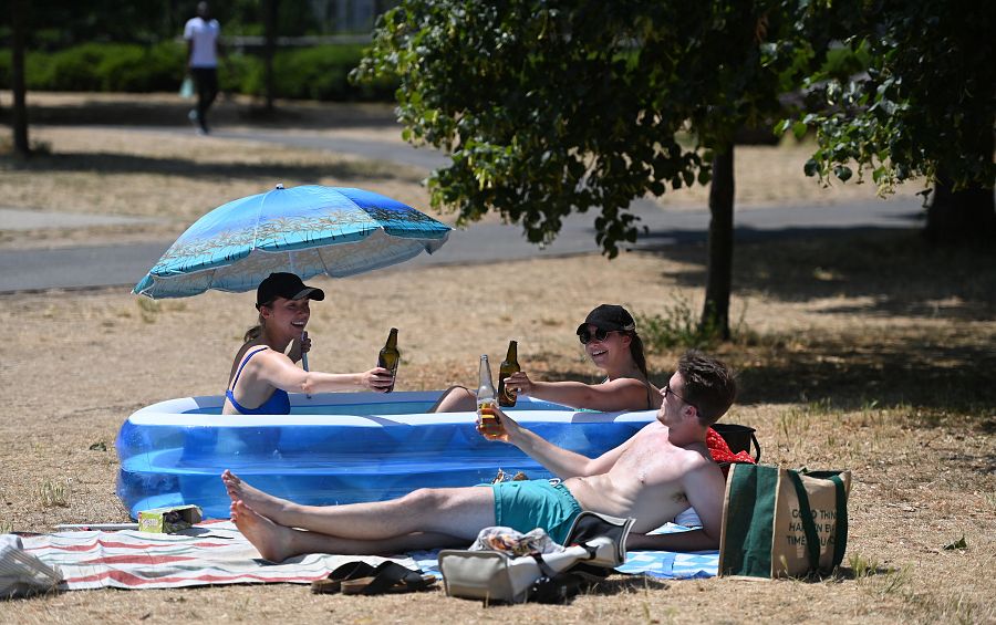 Unos amigos se sientan en una piscina infantil en un parque del centro de Londres.