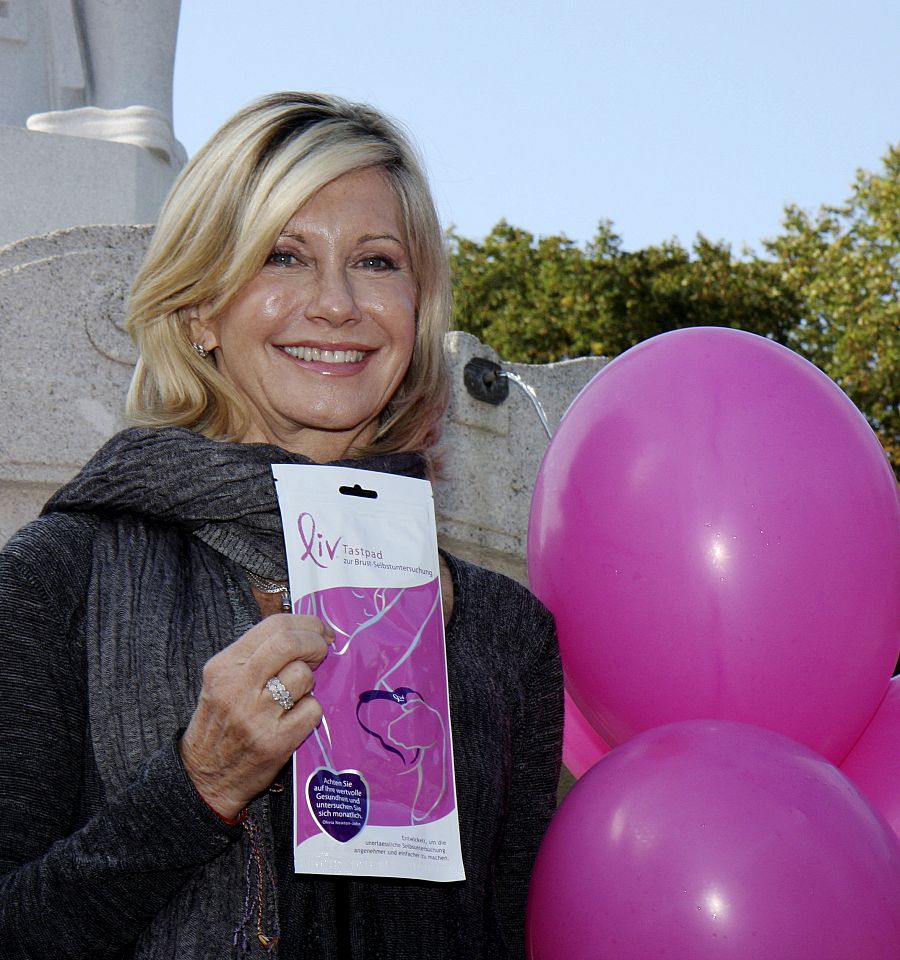 La actriz británica Olivia Newton-John posa con una cinta rosa antes de una visita a Viennal, el lunes 5 de octubre de 2009, en el día internacional del cáncer de mama.